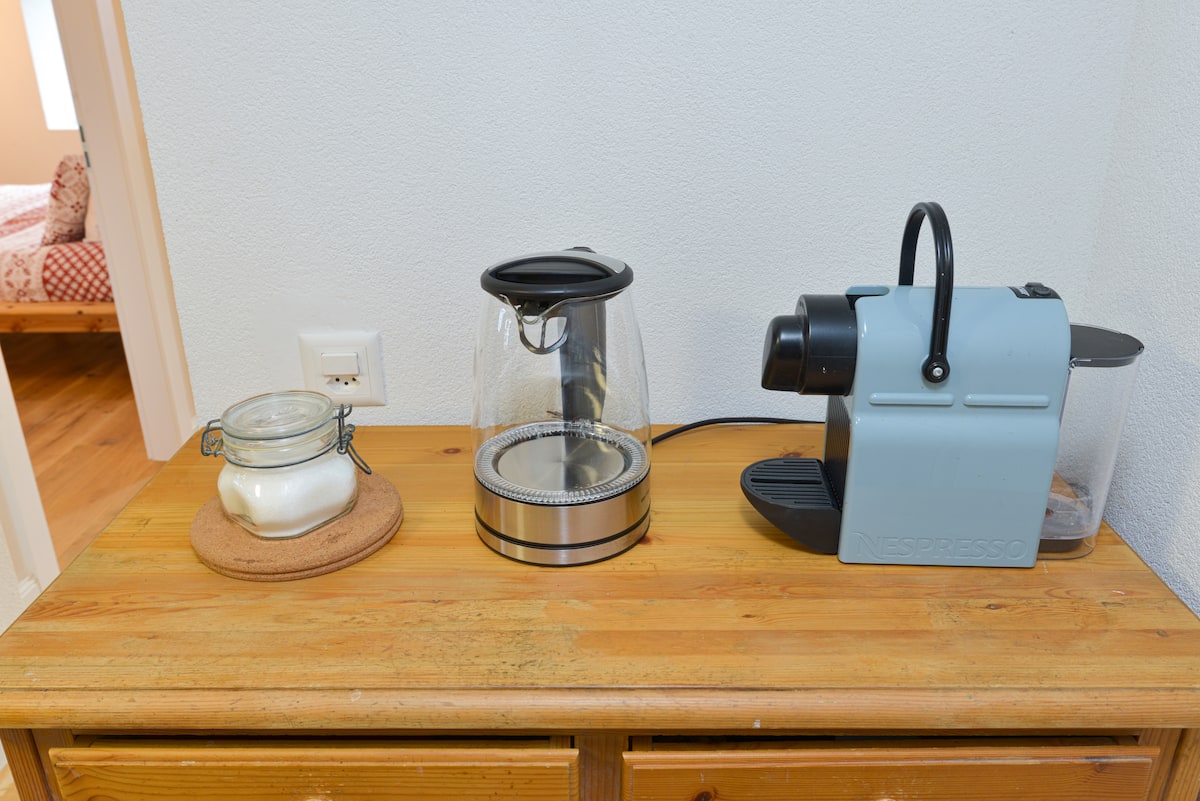Nespresso corner with glass kettle on a wooden sideboard