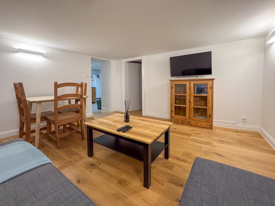 Living-dining room with wooden table, sofas and TV cabinet